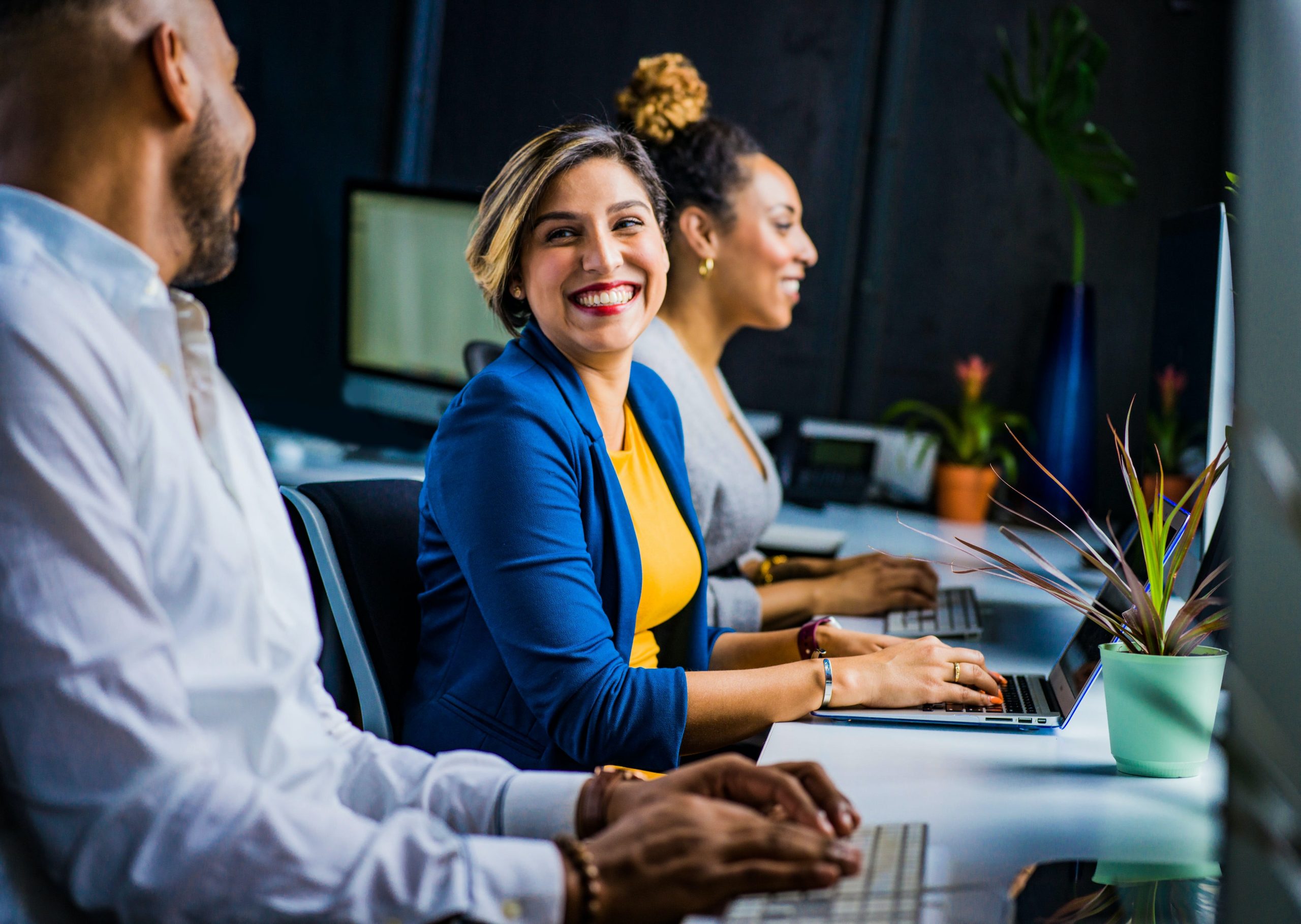 Three people sitting at their desk in an office environment.