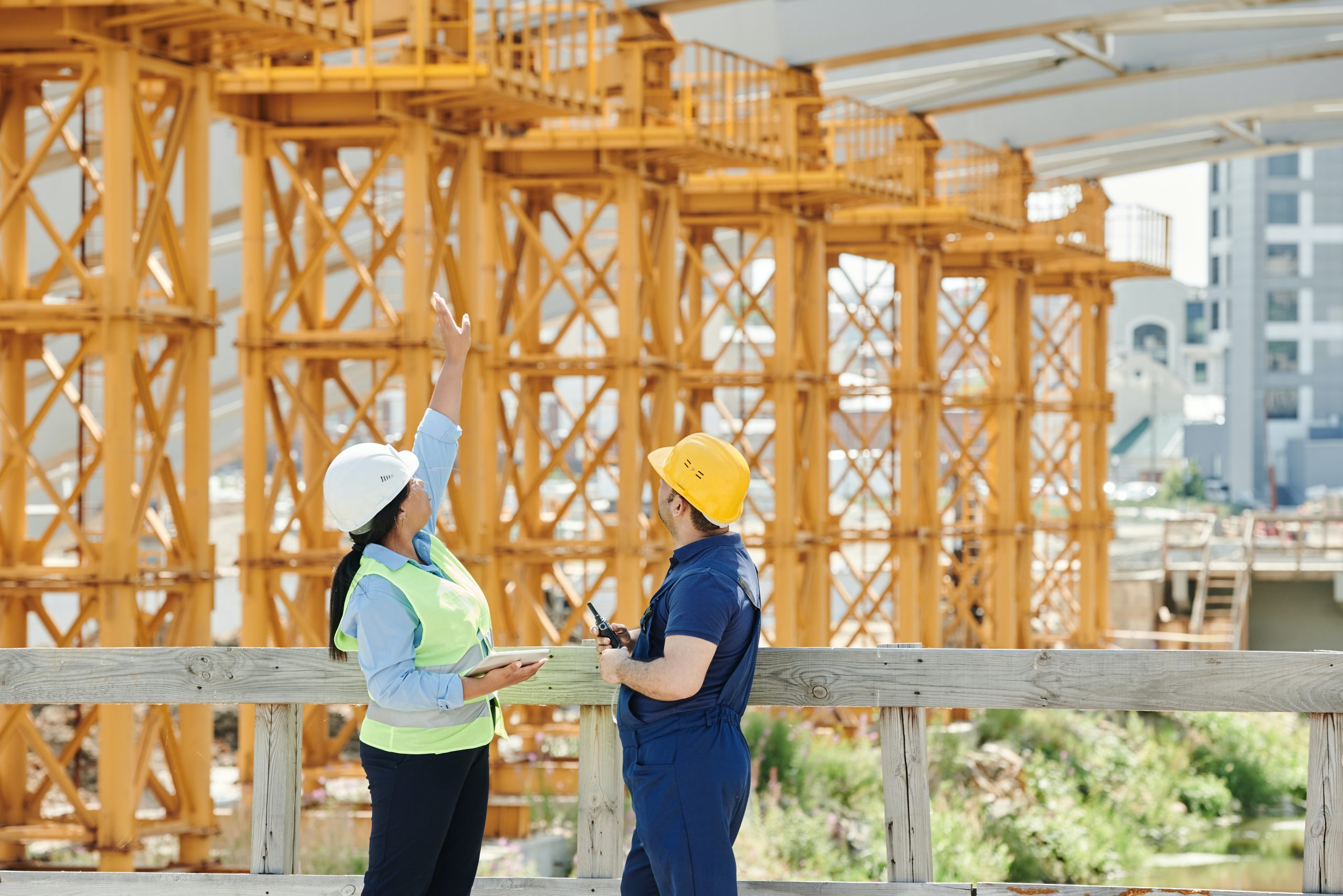 two individuals in construction vests looking at a unfinished structure
