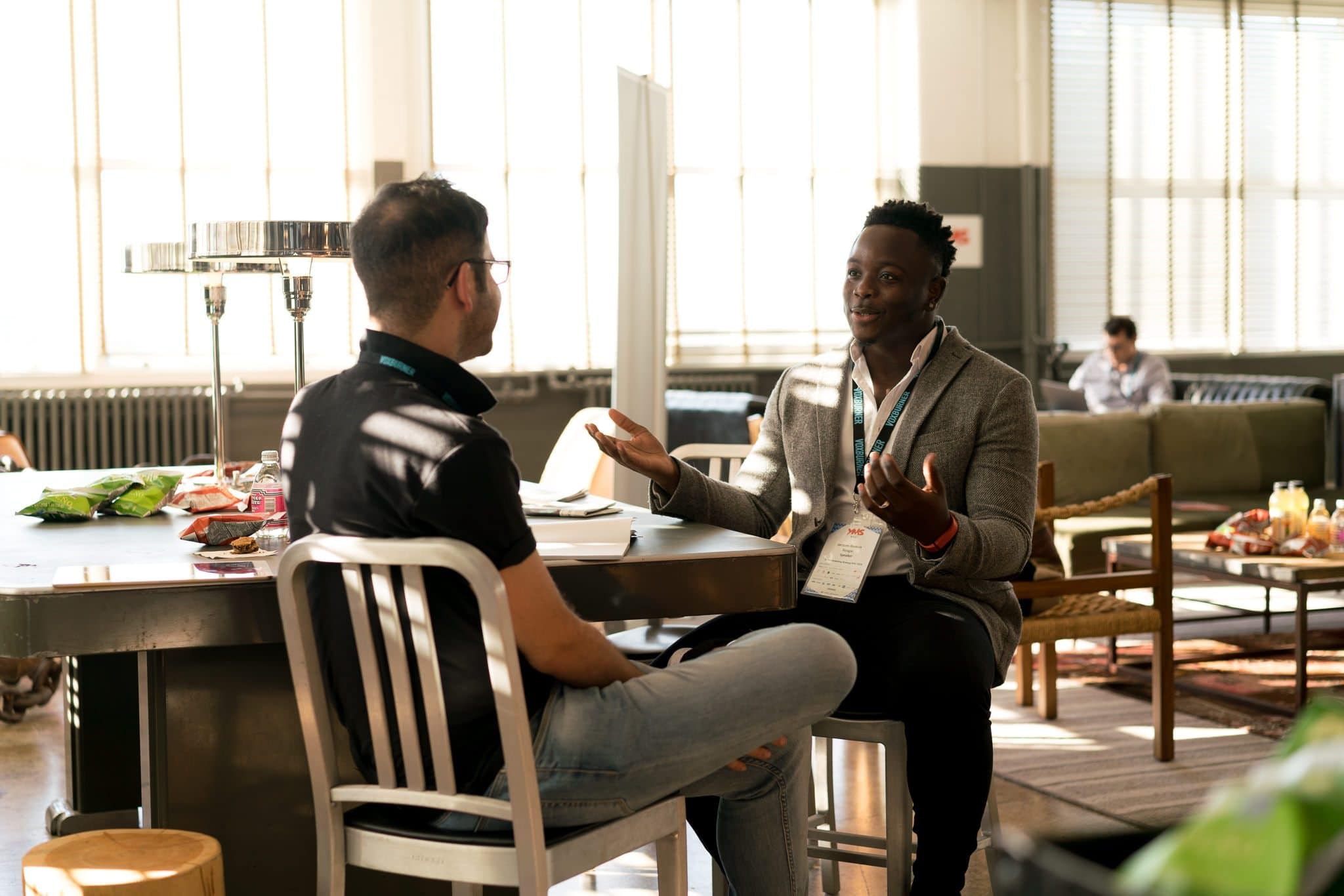 Two people sitting on chairs facing each other talking.