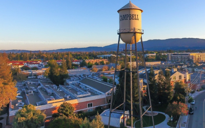 City of Campbell water tower with buildings below and a small mountain range behind