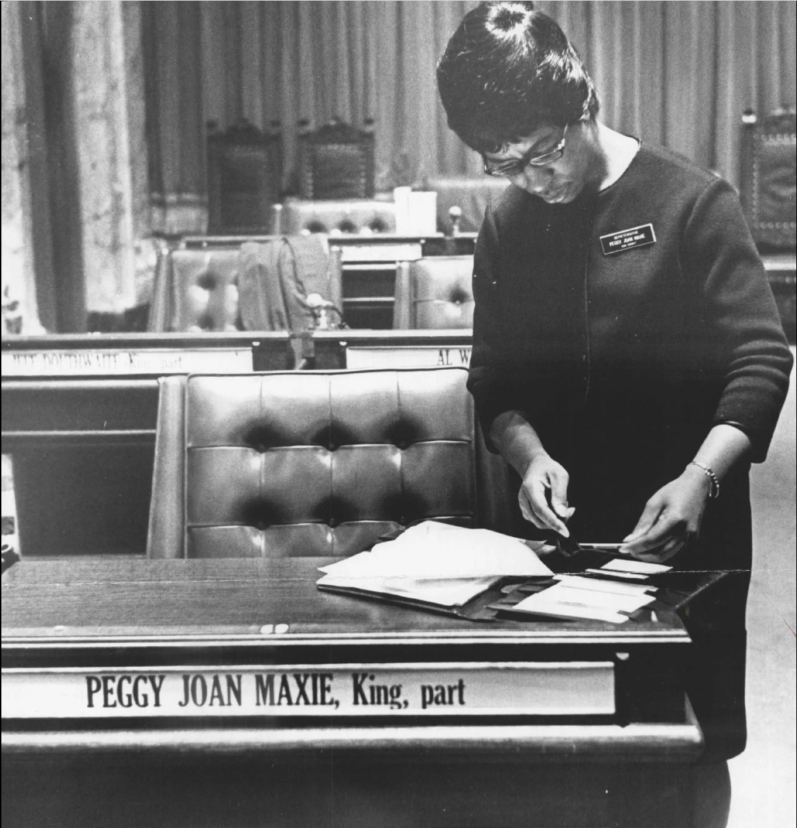 Picture of a Peggy Joan Maxie with a desk looking at an open folder.